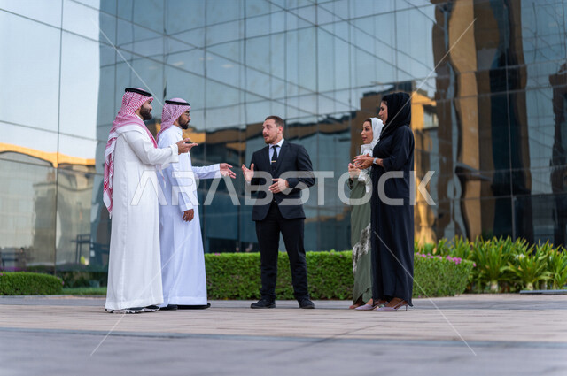 A Saudi work team outside the company building, a dialogue and discussion with a client wearing a formal suit, follow-up and discussion of business, Saudi professions and jobs, the headquarters of a Saudi company, co-workers, partnership and cooperation