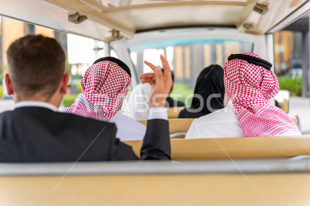 A corner from the back of a group of Saudi Arab people inside an electric car specialized in transporting passengers, a visit and tourism, a business trip for a Saudi Gulf business team, an electric tourist car