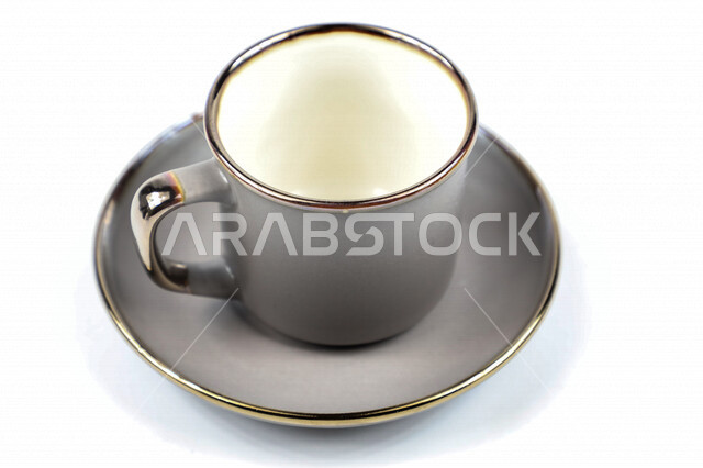 صورة مقربة لكوب رمادي اللون، فنجان رمادي فارغ، طبق صغير، كوب زجاجي، خلفية بيضاء