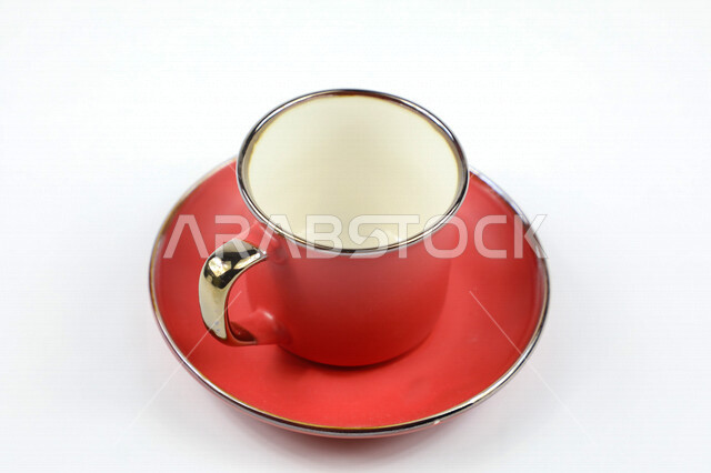 صورة مقربة لكوب احمر اللون، فنجان احمر فارغ، طبق صغير، كوب زجاجي على طبق زجاجي، خلفية بيضاء