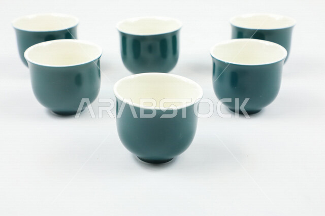 صورة مقربة لمجموعة من الفناجين الصغيرة، اكواب زرقاء فارغة، فنجان ضيافة صغير، كوب زجاجي، خلفية بيضاء