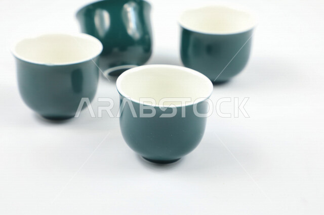 صورة مقربة لمجموعة من الفناجين الصغيرة، اكواب زرقاء فارغة، فنجان ضيافة صغير، كوب زجاجي، خلفية بيضاء