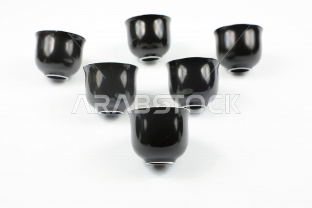 صورة مقربة لمجموعة من الفناجين الصغيرة، اكواب سوداء فارغة، فنجان ضيافة صغير، كوب زجاجي، خلفية بيضاء