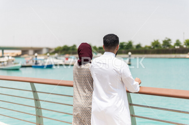 زوجان عربيان سعوديان خليجيان  في ممشى كورنيش جده, الإستمتاع بمشاهدة المناظر الجميله على شاطيء البحر الأحمر, دردشه ومحادثات, أنشطه ترفيهيه,التنزه في مارينا جده, عطله صيفيه, السياحه في المملكه العربيه السعوديه