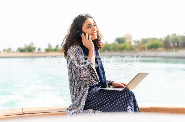 إمرأه عربيه سعوديه خليجيه على متن يخت, إجراء مكالمه هاتفيه عبر الهاتف المحمول, إستخدام جهاز الحاسوب المحمول, إدارة الأعمال عن بعد, التواصل الإجتماعي, الإبحار في القوارب والسفن, جولات بحريه على كورنيش جده, رحلات بحريه في مارينا جده, السياحه في السعوديه