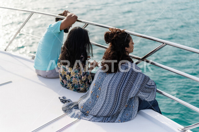  تصوير من الخلف لمجموعه من الأصدقاء العرب السعوديون الخليجيون يجلسون في متن يخت وسط البحر, متعة الإبحار في القوارب والسفن, رحلات جماعيه, جولات بحريه على كورنيش جده, أنشطه ترفيهيه, رحلات بحريه في مارينا جده, عطله صيفيه, السياحه في السعوديه