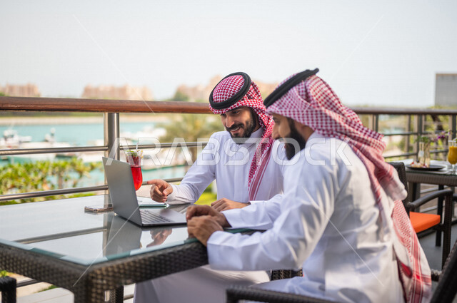 زملاء عمل عرب خليجيون سعوديون مجتمعون في مقهى احد الفنادق الخليجية، استخدام الحاسوب المحمول، حوار ونقاش عمل خارج الشركه، انجهاز مهام العمل، إدارة الأعمال عن بعد، توزيع مهام العمل بين الزملاء، قضاء أجمل الأوقات في أفضل الفنادق الخليجية، سياحة وفندقة