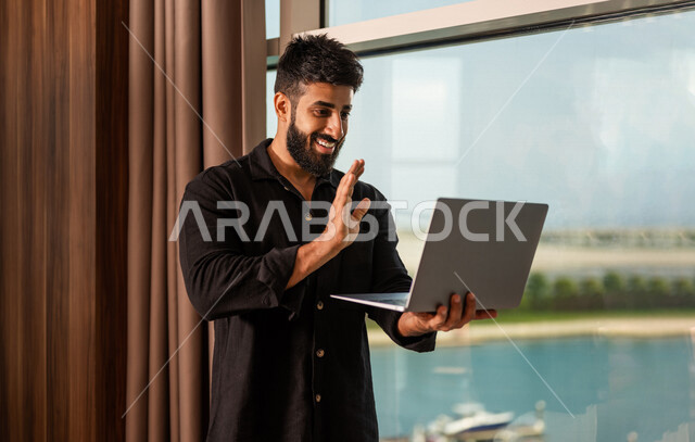 شاب عربي خليجي سعودي يرتدي زي كاجوال صيفي، اجراء مكالمة فيديو ، القاء التحية ، بث فيديو مباشر، دردشة وتواصل، عطلة صيفية ، التعارف و التواصل الاجتماعي ، صداقات عبر الانترنت ، التواصل مع العملاء