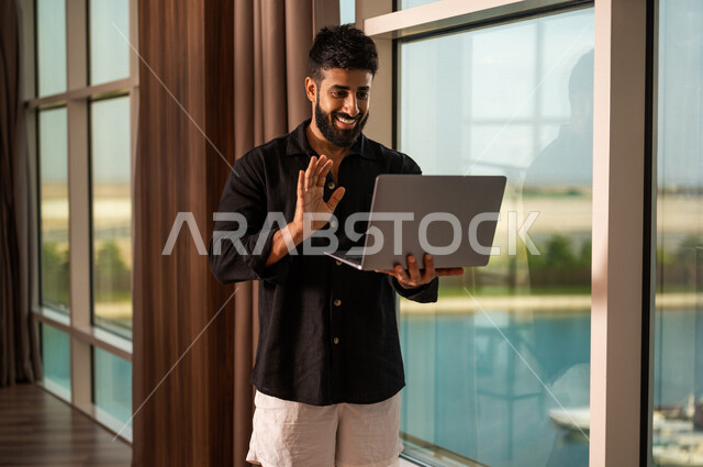 شاب عربي خليجي سعودي يرتدي زي كاجوال صيفي، اجراء مكالمة فيديو ، القاء التحية ، بث فيديو مباشر، دردشة وتواصل، عطلة صيفية ، التعارف و التواصل الاجتماعي ، صداقات عبر الانترنت ، التواصل مع العملاء