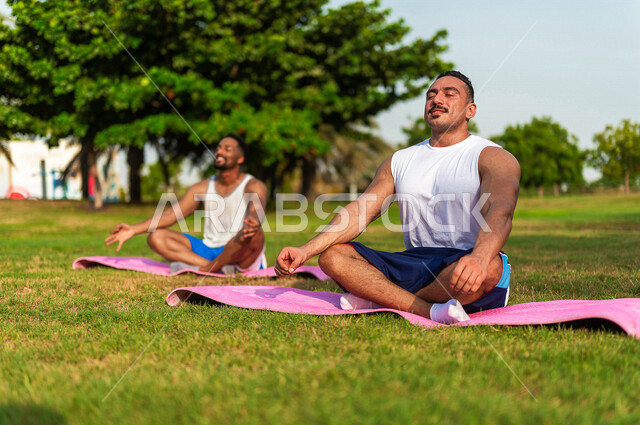 شابان عربيان خليجيان سعوديان يمارسان رياضة اليوغا التأملية، ممارسة نشاط رياضي، أنشطة و تمارين رياضية، التأمل و الاسترخاء، الرياضة والنشاط البدني، تمارين اللياقة البدنية، أسلوب حياة صحي، لياقة و رشاقة