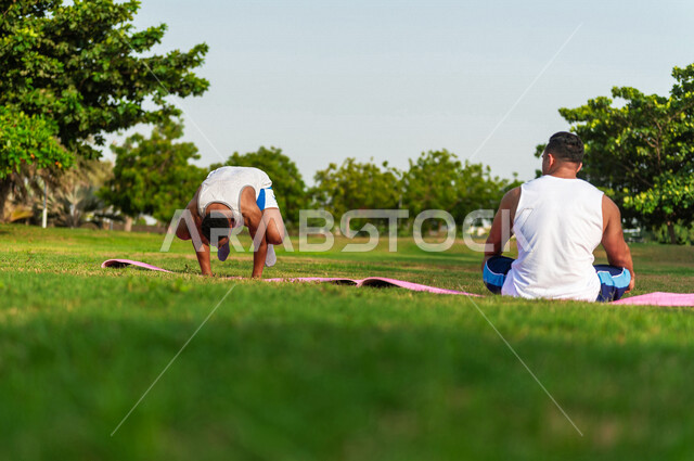 صورة من الخلف لشابان عربيان خليجيان سعوديان يمارسان رياضة اليوغا التأملية، ممارسة نشاط رياضي، أنشطة و تمارين رياضية، التأمل و الاسترخاء، الرياضة والنشاط البدني، تمارين اللياقة البدنية، أسلوب حياة صحي، لياقة ورشاقة