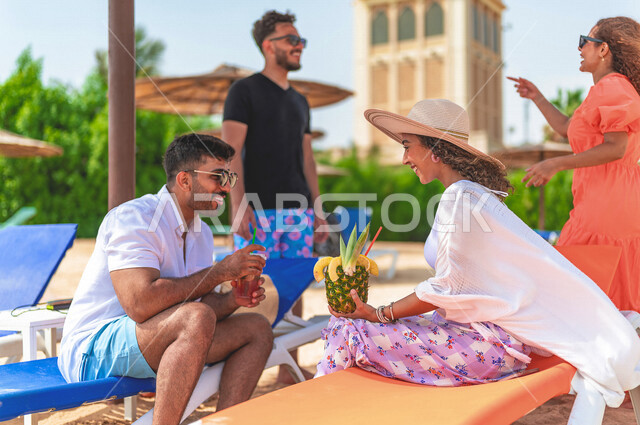 مجموعة من الأصدقاء العرب الخليجيين السعوديين يتقابلون على شاطيء بحر جدة، الاستمتاع بالمشروبات الصيفية  المنعشة على شاطئ البحر، دردشة ومحادثات، المتعة والاستجمام على  بحر جدة السياحي، أزياء صيفية