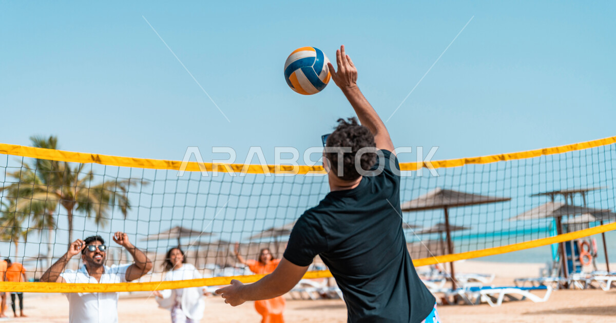 A group of Saudi Arabian Gulf friends playing beach volleyball on the