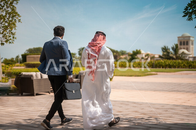 تصوير من الخلف لرجال أعمال عرب سعوديون خليجيون يقومون بالمشي خارج مبنى الشركة، محادثات عامه, نقاشات عمل, زملاء عمل, إنتهاء الدوام، خروج الموظفين، مهن ووظائف سعودية، شركات ومكاتب عربيه سعوديه خليجيه في المملكه العربيه السعوديه