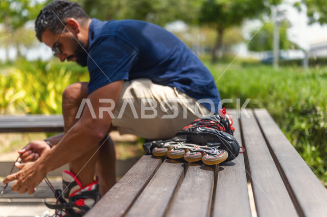 صورة مقربة لرجل عربي خليجي سعودي، الإستعداد لإرتداء الزلاجات الدوارة في إحدى الحدائق الترفيهية بالمملكة العربية السعودية، قضاء أوقات ممتعة، أنشطة ترفيهية، ممارسة رياضة تزلج بالعجلات