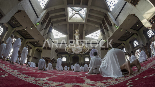 A group of Muslim pilgrims wearing the Ihram dress, performing prayer at the Sayeda Aisha Mosque in the Miqat al-Tana’im in Makkah, preparing to perform Hajj in Makkah al-Mukarramah, Saudi Arabia, Hajj season 2022, worshiping and getting closer to God