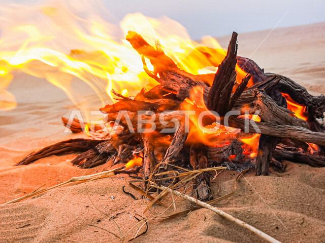 النيران المشتعلة في الحطب نهارا ، اللهب الأحمر المشتعل في رحلة تخييم بالصحراء ، التخييم في صحراء المملكة العربية السعوديه، البر و التخييم, التدفئه بإشعال الحطب