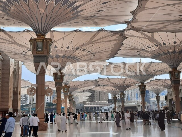 The courtyard of the Prophet’s Mosque in Medina, Saudi Arabia, worship and getting closer to God, the Prophet’s Mosque, holy Islamic places, Muslims walking in the outer complex of the Prophet’s Mosque in Medina, electronic umbrellas