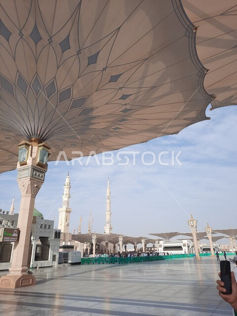 ساحة المسجد النبوي الشريف في المدينة المنورة بالمملكة العربية السعودية، العبادة والتقرب الى الله، الحرم النبوي الشريف، أماكن إسلامية مقدسة، المسلمون يمشون في المجمع الخارجي للمسجد النبوي في المدينة المنورة، المظلات الإلكترونية