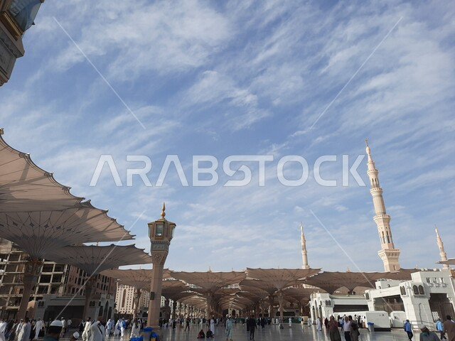 ساحة المسجد النبوي الشريف في المدينة المنورة بالمملكة العربية السعودية، العبادة والتقرب الى الله، الحرم النبوي الشريف، أماكن إسلامية مقدسة، المسلمون يمشون في المجمع الخارجي للمسجد النبوي في المدينة المنورة، المظلات الإلكترونية