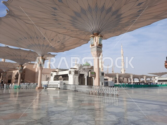 ساحة المسجد النبوي الشريف في المدينة المنورة بالمملكة العربية السعودية، العبادة والتقرب الى الله، الحرم النبوي الشريف، أماكن إسلامية مقدسة، المسلمون يمشون في المجمع الخارجي للمسجد النبوي في المدينة المنورة، المظلات الإلكترونية