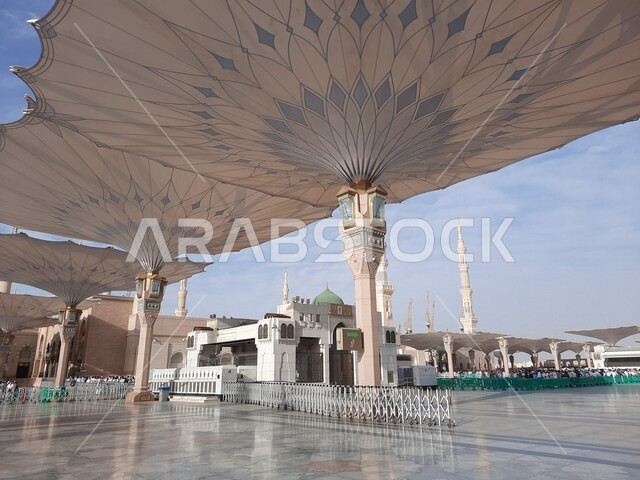 ساحة المسجد النبوي الشريف في المدينة المنورة بالمملكة العربية السعودية، العبادة والتقرب الى الله، الحرم النبوي الشريف، أماكن إسلامية مقدسة، المسلمون يمشون في المجمع الخارجي للمسجد النبوي في المدينة المنورة، المظلات الإلكترونية