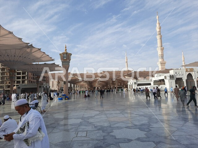 ساحة المسجد النبوي الشريف في المدينة المنورة بالمملكة العربية السعودية، العبادة والتقرب الى الله، الحرم النبوي الشريف، أماكن إسلامية مقدسة، المسلمون يمشون في المجمع الخارجي للمسجد النبوي في المدينة المنورة، المظلات الإلكترونية