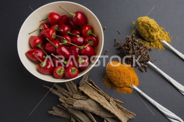 صورة مقربة لمجموعة من التوابل والأعشاب على طاولة الجرافيت، توابل خشنة وناعمة، بهارات، طبق من الفلفل الاحمر الحار