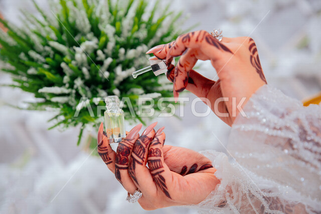 Close-up of a bride wearing a white wedding suit and applying nail polish, henna engraving of the bride, a beautiful view of the bride on her wedding day, the night of life, nail care, occasions and weddings