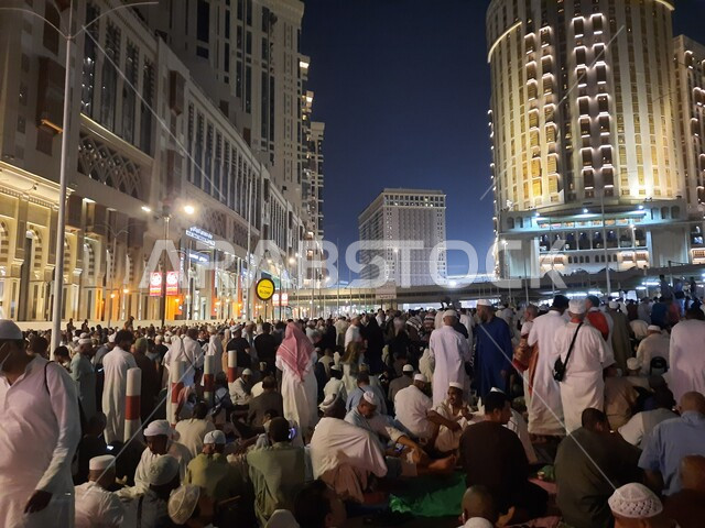  مجموعة من زوار بيت الله الحرام يجلسون في شوارع مكة المكرمة بالمملكة العربية السعودية ليلا، الشوارع والطرقات، الحجاج والمعتمرين، ابراج وفنادق مكة، معالم السعودية، السياحة في السعودية