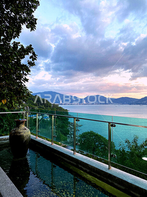 صورة مقربة لشرفة مطلة على شاطئ البحر، الاشجار والنباتات الخضراء، الجبال والمرتفعات، سماء ملبدة بالسحب، مناظر طبيعية خلابة، اماكن ترفيهية سياحية
