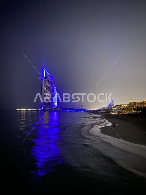 An aesthetic image of Burj Al Arab overlooking the Arabian Gulf in the Emirate of Dubai in the United Arab Emirates, tourism in the Emirates, architectural art in the Emirates, Burj Al Arab illuminated in blue, skyscraper, famous Dubai tourist attractions