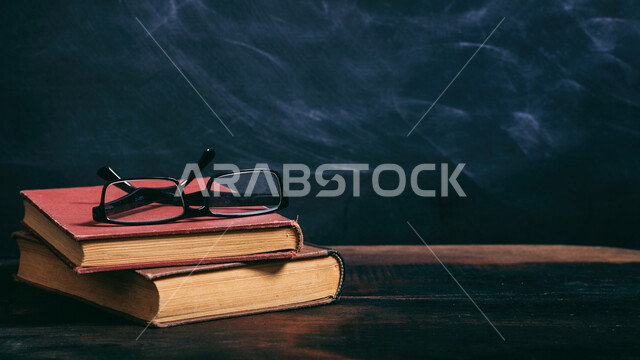 مجموعة من الكتب على طاولة خشبية، قراءة الكتب ، القراءة والثقافة ، الكتب القديمة ، نظارة طبية فوق الكتب ، هواية القراءة ،القراءة والتعلم ، التعليم والدراسة ، قصص و روايات