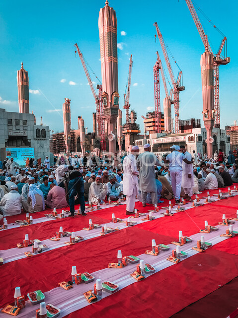 مجموعة من المسلمين يجلسون على مائدة الافطار الجماعي في ساحة المسجد النبوي الشريف في المدينة المنورة بالمملكة العربية السعودية، الحرم النبوي الشريف، مائدة الافطار، أماكن إسلامية مقدسة، المجمع الخارجي للمسجد النبوي الشريف، المعالم الدينية بالسعودي