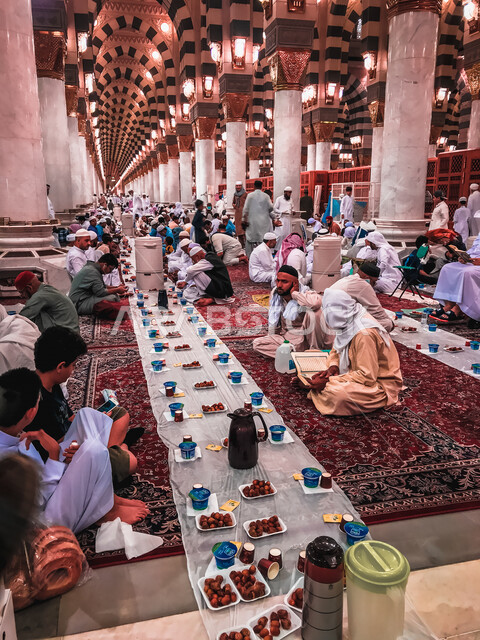 مجموعة من المسلمين يجلسون على مائدة الافطار الجماعي في المسجد النبوي الشريف في المدينة المنورة بالمملكة العربية السعودية، الحرم النبوي الشريف، مائدة الافطار، أماكن إسلامية مقدسة، المسجد النبوي الشريف، المعالم الدينية بالسعودي
