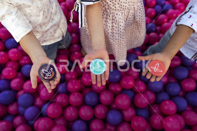 صورة مقربة لايدي مجموعة من الاطفال يحملون قطع  بلاستيكية ملونة بشعار مركز الملك عبدالعزيز الثقافي العالمي (إثراء)، موسم الابداع (تنوين)، منارة ثقافية، تنمية مهارات الطفل، رعاية و اثراء الأطفال، اللعب والتعلم والاستكشاف