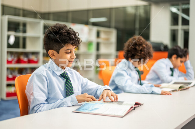 طلاب عرب سعوديون خليجيون يجلسون في المكتبة المدرسية، الاستمتاع بقراءة الكتب، مفهوم التعليم الذاتي, مكتبة المدرسة، بيئه مدرسيه تعليميه متطوره, المدارس المبتكره, جودة التعليم, مدارس أكاديميه في المملكة العربية السعودية