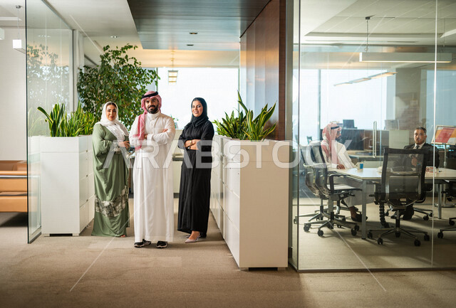 فريق عمل سعودي داخل مقر الشركة ، رجل وسيدات أعمال ينظرون إلى الكاميرا بإيدي متقاطعة ، مهن و وظائف سعودية ، شركة سعودية ، زملاء عمل، بيئة العمل ، تحقيق وتطوير الأهداف