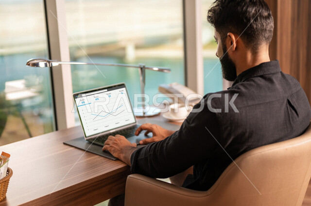 رجل أعمال عربي خليجي سعودي، إستخدام جهاز الحاسوب المحمول، إنجاز مهام العمل، تصفح الإنترنت، جلسة عمل، عقد إجتماع عمل عبر الإنترنت، التسويق الإلكتروني، مهن ووظائف سعودية