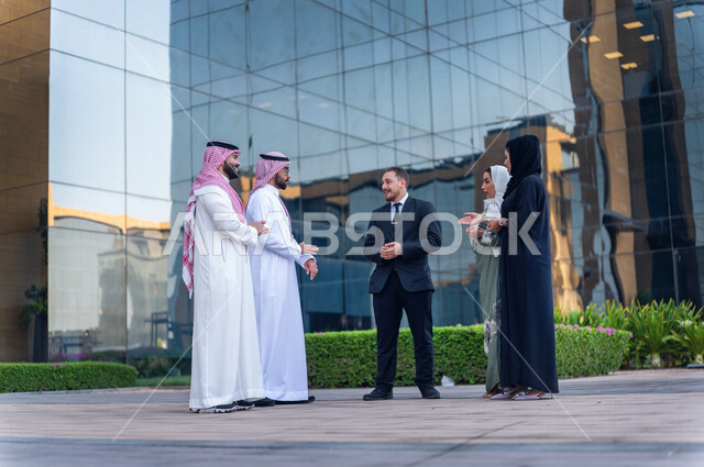 فريق عمل سعودي خارج مبنى الشركة ، حوار ومناقشة مع عميل يرتدي البدلة الرسمية ،  متابعة ومناقشة الأعمال ، مهن ووظائف سعودية ، مقر شركة سعودية ، زملاء عمل، الشراكة والتعاون