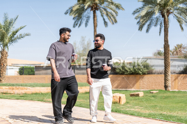 صديقان عربيان خليجيان سعوديان يمارسان الرياضة الصباحية، ممارسة رياضة المشي الهواء الطلق مع احتساء كوب من القهوة، دردشة ومحادثات، نشاطات شبابية، رحلة ترفيهية، طريق ممشى في الحدائق والمنتزهات، نزهه في الهواء الطلق