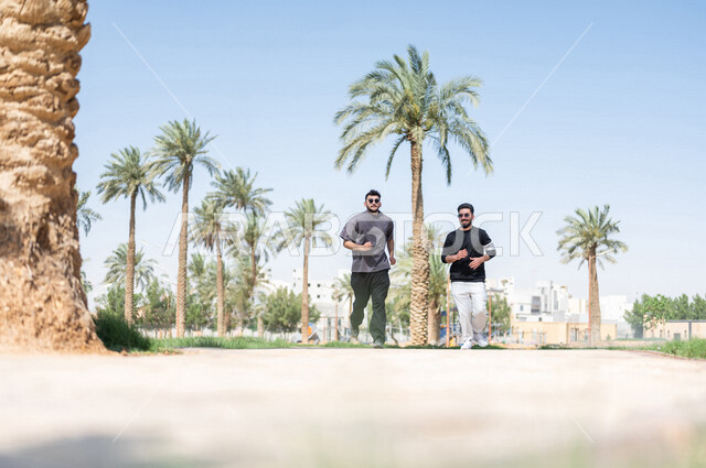 صديقان عربيان خليجيان سعوديان يمارسان رياضة الجري، الصحة واللياقة الجسدية، نشاط بدني في الهواء الطلق، التنزه في الحدائق العامة، تمارين اللياقة البدنية، ممارسة نشاط رياضي، لياقة ورشاقة، طريق ممشى في الحدائق والمنتزهات، نزهه في الهواء الطلق