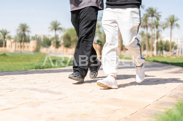 صورة مقربة لصديقان عربيان خليجيان سعوديان يمارسان الرياضة الصباحية، ممارسة رياضة المشي، قضاء اوقات ممتعة في الحدائق العامة، دردشة ومحادثات، نشاط بدني، طريق ممشى في الحدائق والمنتزهات، ممارسة التمارين الرياضية، نزهه في الهواء الطلق