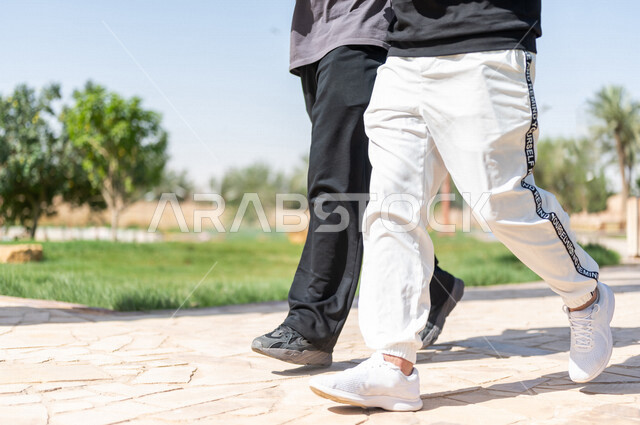 صورة مقربة لصديقان عربيان خليجيان سعوديان يمارسان الرياضة الصباحية، ممارسة رياضة المشي، قضاء اوقات ممتعة في الحدائق العامة، دردشة ومحادثات، نشاط بدني، طريق ممشى في الحدائق والمنتزهات، ممارسة التمارين الرياضية، نزهه في الهواء الطلق