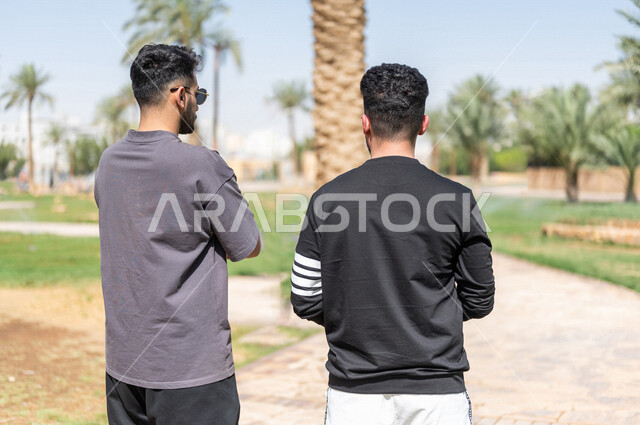صورة من الخلف لصديقان عربيان خليجيان سعوديان يمارسان الرياضة الصباحية، ممارسة رياضة المشي، قضاء اوقات ممتعة في الحدائق العامة، دردشة ومحادثات، نشاط بدني، طريق ممشى في الحدائق والمنتزهات، ممارسة التمارين الرياضية، نزهه في الهواء الطلق