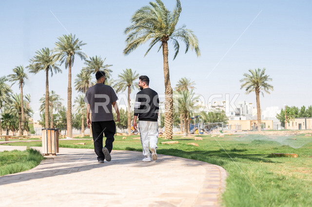 صورة من الخلف لصديقان عربيان خليجيان سعوديان يمارسان الرياضة الصباحية، ممارسة رياضة المشي، قضاء اوقات ممتعة في الحدائق العامة، دردشة ومحادثات، نشاط بدني، طريق ممشى في الحدائق والمنتزهات، ممارسة التمارين الرياضية، نزهه في الهواء الطلق