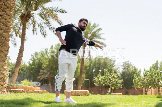 شاب عربي خليجي سعودي يمارس تمارين التمدد، تمديد عضلات الجسم، ممارسة نشاط رياضي، أنشطة و تمارين رياضية، الرياضة والنشاط البدني، تمارين اللياقة البدنية، أسلوب حياة صحي، لياقة ورشاقة