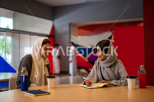 A close-up photo of two Saudi Arabian Gulf students in the university cafe, cooperation and participation, performance of duties, advanced academic colleges and universities, two Saudi Arabian Gulf female employees in the company cafe, conversations and d
