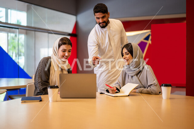A close-up photo of a group of Arab Saudi Gulf university students in the university cafe, cooperation and sharing, working on the computer, advanced academic universities, Saudi Arab Gulf employees in the company cafe, conversations and discussions, busi