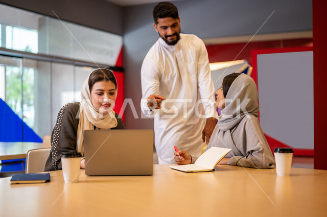 A close-up photo of a group of Arab Saudi Gulf university students in the university cafe, cooperation and sharing, working on the computer, advanced academic universities, Saudi Arab Gulf employees in the company cafe, conversations and discussions, busi
